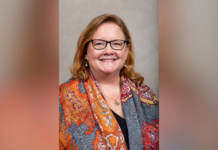 Dr. Sharon Augustine appointed interim dean of Tift College of Education Woman with glasses and long hair, smiling, wearing an orange patterned scarf over a dark top, in front of a neutral background.