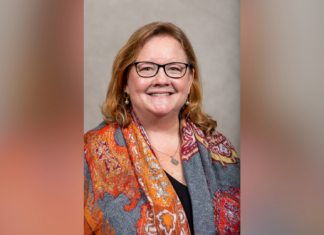 Dr. Sharon Augustine appointed interim dean of Tift College of Education Woman with glasses and long hair, smiling, wearing an orange patterned scarf over a dark top, in front of a neutral background.