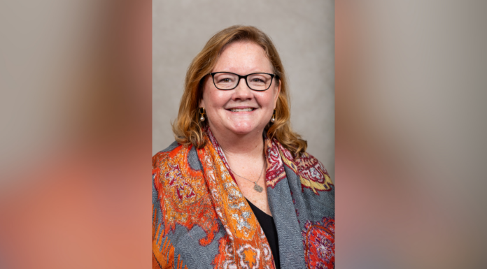 Dr. Sharon Augustine appointed interim dean of Tift College of Education Woman with glasses and long hair, smiling, wearing an orange patterned scarf over a dark top, in front of a neutral background.