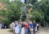 Poland study abroad program brings history, literature to life A group of people pose in front of a large outdoor dragon statue surrounded by trees and rocky terrain.