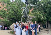 Poland study abroad program brings history, literature to life A group of people pose in front of a large outdoor dragon statue surrounded by trees and rocky terrain.