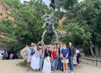 Poland study abroad program brings history, literature to life A group of people pose in front of a large outdoor dragon statue surrounded by trees and rocky terrain.