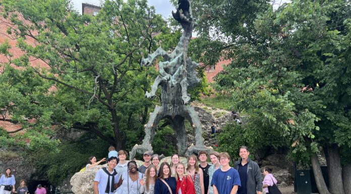 Poland study abroad program brings history, literature to life A group of people pose in front of a large outdoor dragon statue surrounded by trees and rocky terrain.
