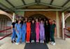 Mercer On Mission program fills gap in medical care in Honduran community A group of people in colorful scrubs stands together under a covered walkway in front of a brick building.