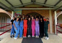 Mercer On Mission program fills gap in medical care in Honduran community A group of people in colorful scrubs stands together under a covered walkway in front of a brick building.