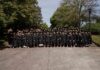 Physician assistant studies students earn perfect pass rate on national certifying exam Large group of graduates in black gowns pose together outdoors in front of trees on a sunny day.