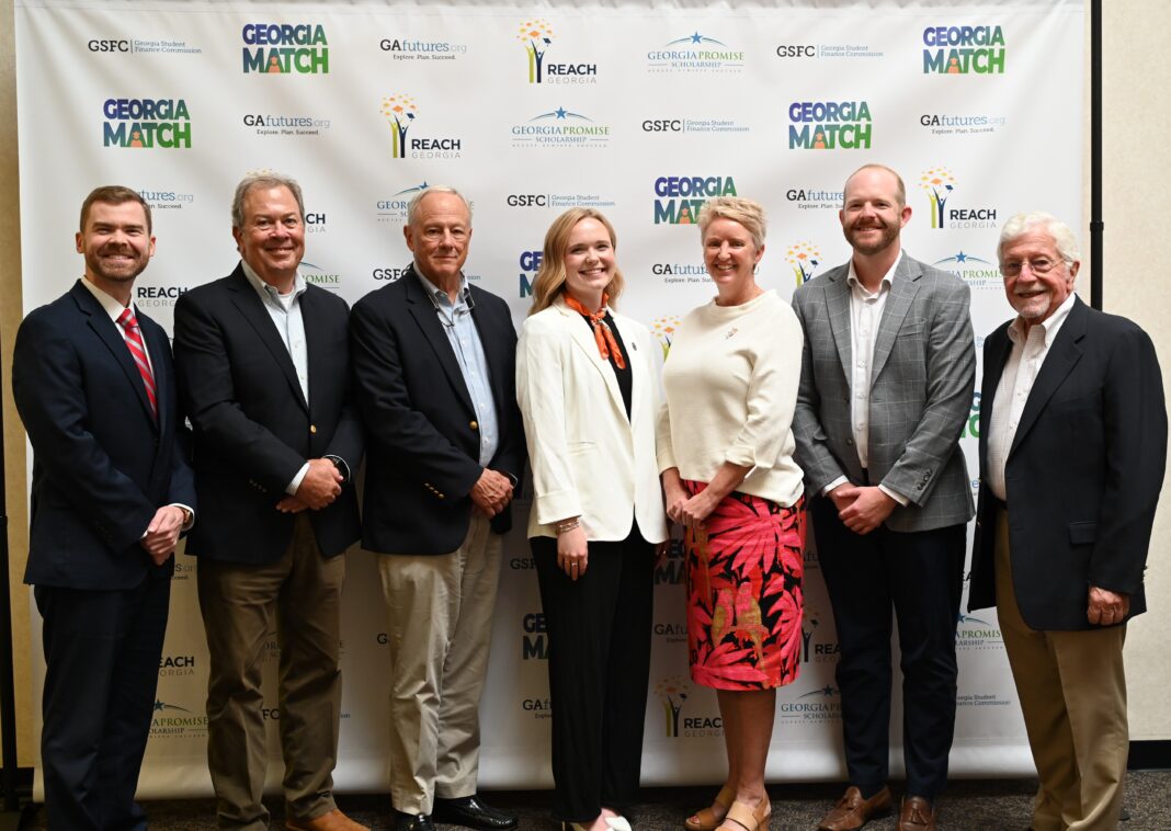 3 (1) Seven people standing in a row and posing for a photo in front of a Georgia Match event backdrop.