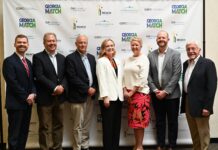 Alumna Chloe Paulk selected as Georgia Student Finance Commission Moment of Impact speaker Seven people standing in a row and posing for a photo in front of a Georgia Match event backdrop.