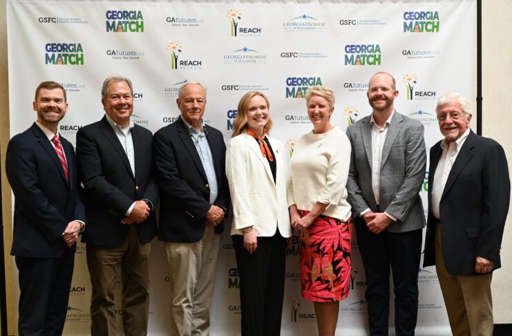 Seven people standing in a row and posing for a photo in front of a Georgia Match event backdrop.