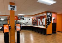 What’s new with Atlanta campus dining this year Fast food restaurant interior with self-order kiosks, serving counter, and bear mascot wall art.