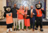 Mercer unveils plans for nationally televised FCS kickoff, free concert series Five people, including two bear mascots, pose on stage with pom-poms and a foam finger at an indoor event.