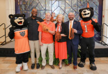 Mercer unveils plans for nationally televised FCS kickoff, free concert series Five people, including two bear mascots, pose on stage with pom-poms and a foam finger at an indoor event.