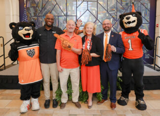 Mercer unveils plans for nationally televised FCS kickoff, free concert series Five people, including two bear mascots, pose on stage with pom-poms and a foam finger at an indoor event.
