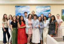 Mercer Law receives top national honor for Student Bar Association A group of fourteen people stand indoors, smiling at the camera, in front of two abstract blue and green paintings.