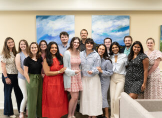 Mercer Law receives top national honor for Student Bar Association A group of fourteen people stand indoors, smiling at the camera, in front of two abstract blue and green paintings.