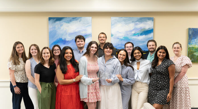Mercer Law receives top national honor for Student Bar Association A group of fourteen people stand indoors, smiling at the camera, in front of two abstract blue and green paintings.