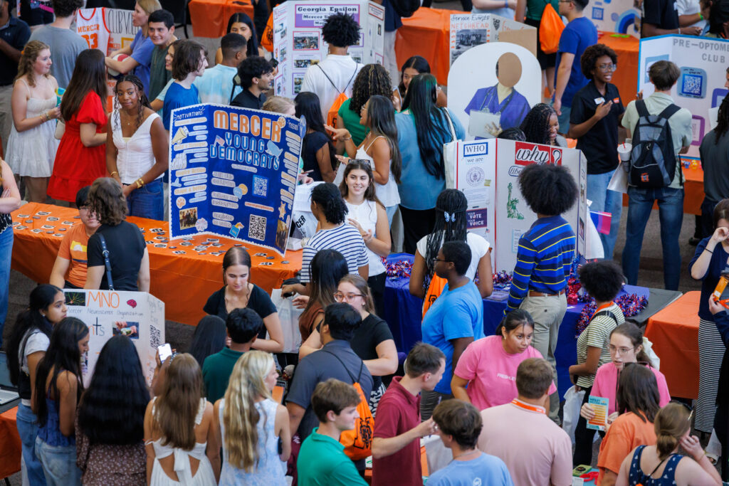 Students gather around club tables with posters at Bear Fair.