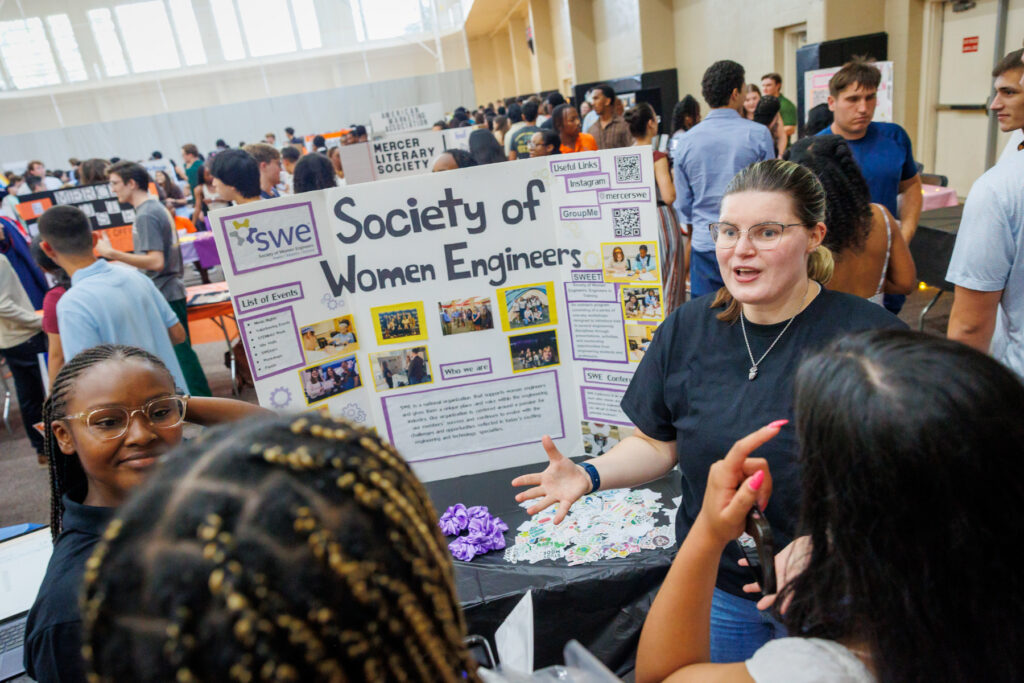 A student speaks with freshmen at a Society of Women Engineers booth during Bear Fair.