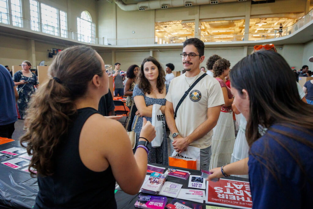 Four people stand at a table with pamphlets at Bear Fair.