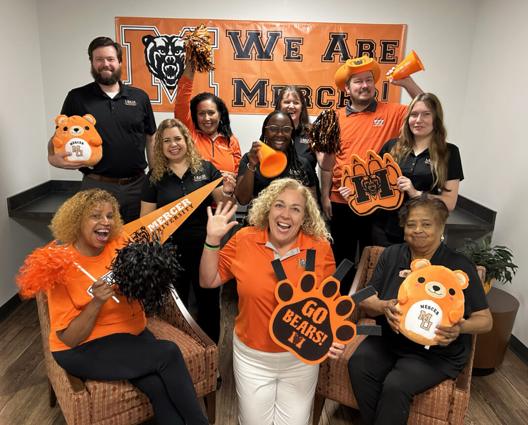 This enthusiastic group in Mercer gear poses with pom-poms, banners, and signs, showing school spirit for the Mercer Bears.