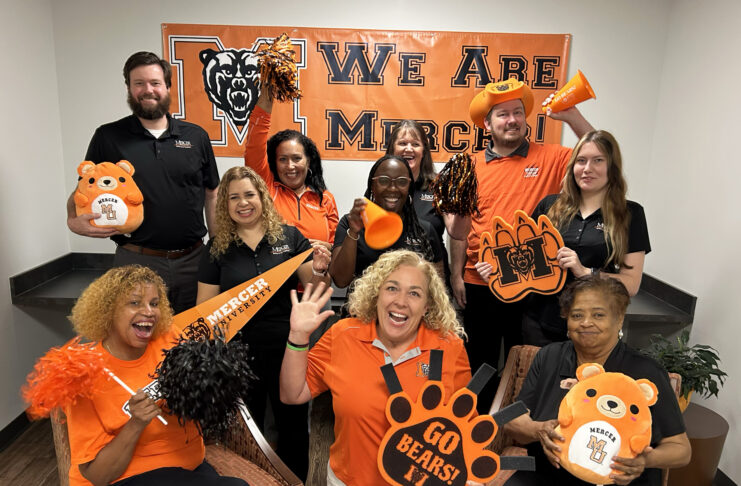 This enthusiastic group in Mercer gear poses with pom-poms, banners, and signs, showing school spirit for the Mercer Bears.
