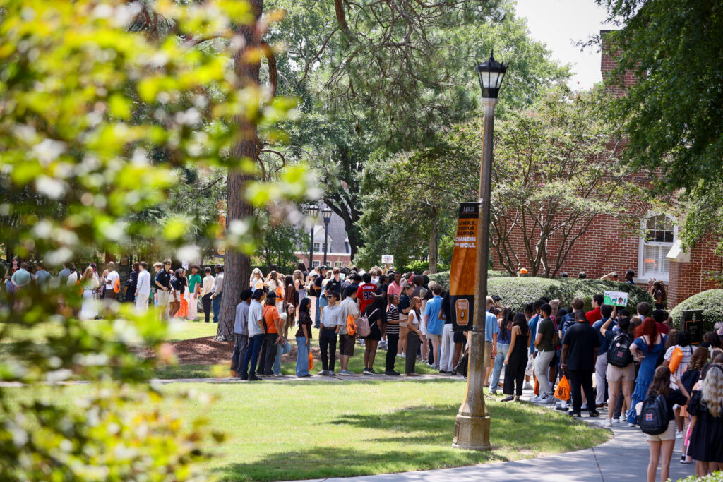 A large group of students lines up outside on Mercer's Macon campus, surrounded by trees and grassy areas.