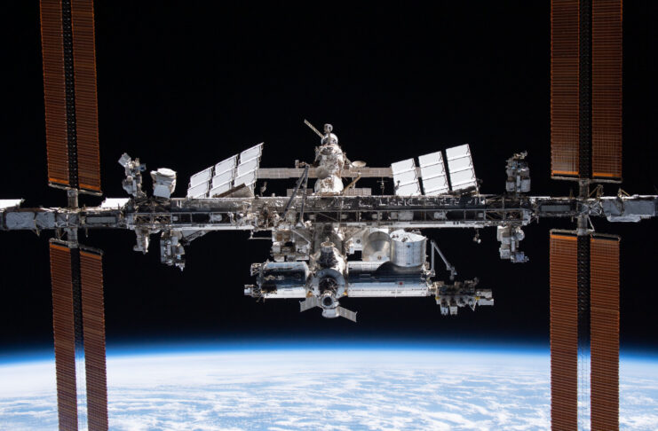 The International Space Station orbits above Earth with solar panels extended against the blackness of space.