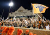 3 things to know about Mercer vs. Furman football game day: Sept. 12, 2026 Fans in body paint cheer and wave sticks in front of Five Star Stadium, holding an orange Mercer Bears flag.