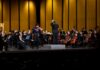 Macon-Mercer Symphony Orchestra’s new season brings big productions, new faces A conductor leads an orchestra on stage with a violin soloist performing at the front.