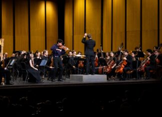 Macon-Mercer Symphony Orchestra’s new season brings big productions, new faces A conductor leads an orchestra on stage with a violin soloist performing at the front.