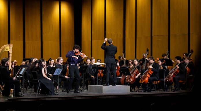 Macon-Mercer Symphony Orchestra’s new season brings big productions, new faces A conductor leads an orchestra on stage with a violin soloist performing at the front.