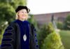 Penny L. Elkins, Ph.D., to be inaugurated as Mercer University’s 19th president, becoming its first woman president Woman in academic regalia and a cap stands outdoors, smiling, with greenery and a building in the background.
