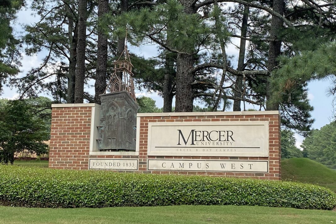 Mercer University - Atlanta Campus - July 23, 2021 Mercer University Campus West entrance sign with brick base, greenery, and trees in the background.