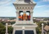 Mercer named a Best Value College for 2027 by The Princeton Review Four people stand in a tower holding a bright orange Mercer University Bears banner overlooking a college campus.