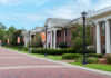 Mercer alumnae rise to top levels of Greek organizations Brick walkways lead past Greek-style housing buildings with white columns and banners on a university campus.