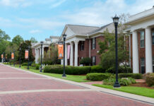 Mercer alumnae rise to top levels of Greek organizations Brick walkways lead past Greek-style housing buildings with white columns and banners on a university campus.