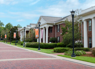 Mercer alumnae rise to top levels of Greek organizations Brick walkways lead past Greek-style housing buildings with white columns and banners on a university campus.
