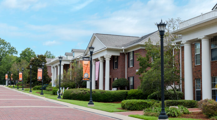 Mercer alumnae rise to top levels of Greek organizations Brick walkways lead past Greek-style housing buildings with white columns and banners on a university campus.