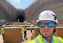 Alumnus supports water projects as district deputy for Corps of Engineers A group of workers in safety vests and helmets stand near a large tunnel under construction; one man is in the foreground.