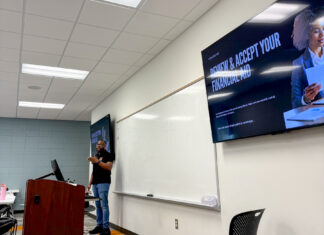 Mercer professor, students hold inaugural camp for teens in foster care A person stands at a podium in a classroom with a screen displaying Review and Accept Your Financial Aid.