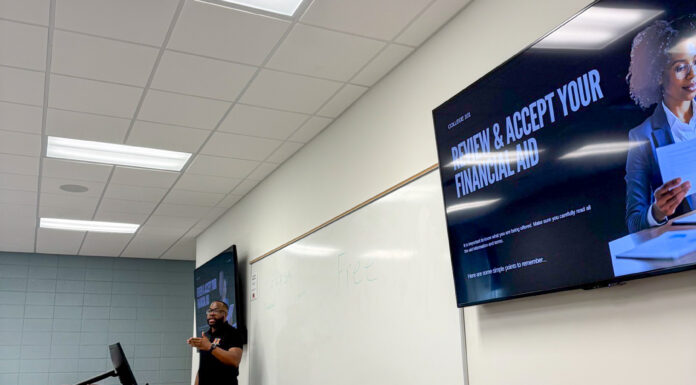 Mercer professor, students hold inaugural camp for teens in foster care A person stands at a podium in a classroom with a screen displaying Review and Accept Your Financial Aid.