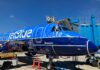 Mercer alumna lands high-flying career with JetBlue A pilot leans out of the cockpit window of a parked JetBlue plane with blue livery near gate D18 at an airport.