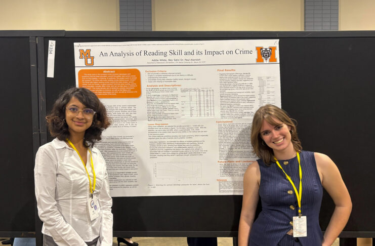 Addie White and Riya Salvi stand in front of a research poster titled An Analysis of Reading Skill and its Impact on Crime.