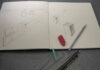 The perspective we choose makes all the difference | Craig McMahan, Ph.D. Open sketchbook with perspective cube drawings, an eraser, and two pencils on a gray surface.