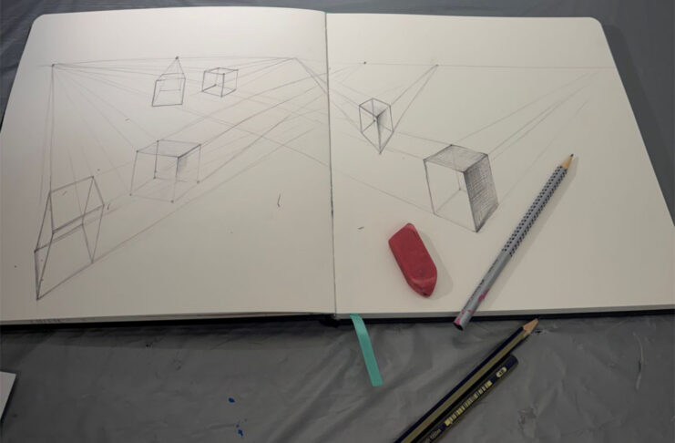 Open sketchbook with perspective cube drawings, an eraser, and two pencils on a gray surface.