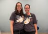 Nursing alumna helps shape care at Children’s Healthcare of Atlanta Two women wearing matching shirts with cartoon ghosts stand side by side, smiling in a room with a light blue wall.