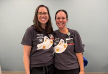 Nursing alumna helps shape care at Children’s Healthcare of Atlanta Two women wearing matching shirts with cartoon ghosts stand side by side, smiling in a room with a light blue wall.