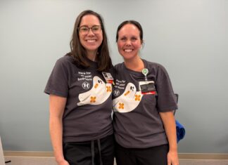 Nursing alumna helps shape care at Children’s Healthcare of Atlanta Two women wearing matching shirts with cartoon ghosts stand side by side, smiling in a room with a light blue wall.