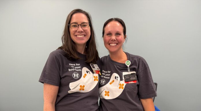 Nursing alumna helps shape care at Children’s Healthcare of Atlanta Two women wearing matching shirts with cartoon ghosts stand side by side, smiling in a room with a light blue wall.