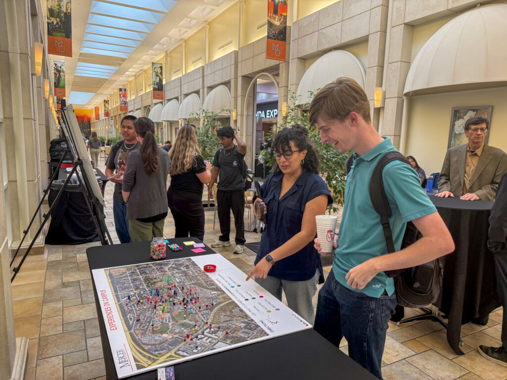 Mercer students gather around a table with a large campus map in the University Center, engaging in an activity.